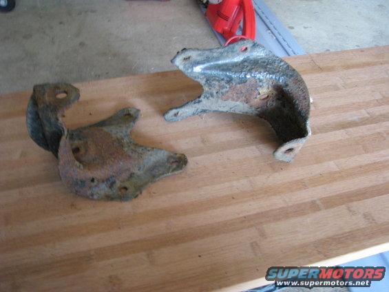 two rusty metal brackets on a wooden surface