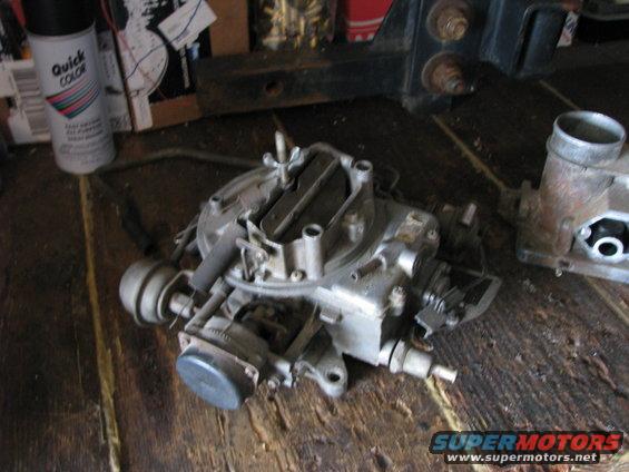 carburetor on a wooden surface with a can of spray paint