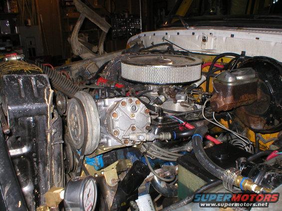 Engine bay with air filter, compressor, and radiator. Visible text: SUPERMOTORS.NET