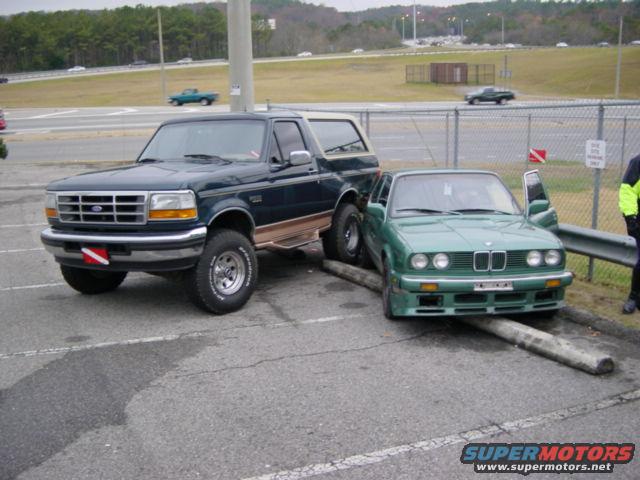 Dark green Ford Bronco parked next to a green BMW 3 Series, both damaged