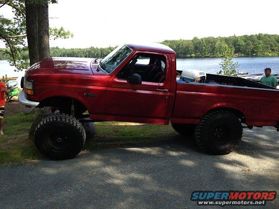 Red 1996 Ford F-150 side view, lifted with large tires