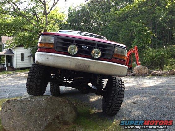 1996 Ford F-150 truck with lifted suspension, front wheel on a rock
