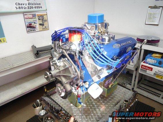 Blue Ford Racing V8 engine with chrome accents and blue spark plug wires on a metal stand