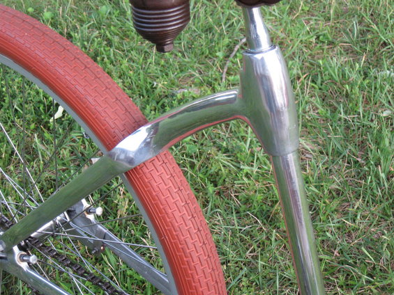 Close-up of a bicycle's rear wheel with a red tire and chrome frame parts