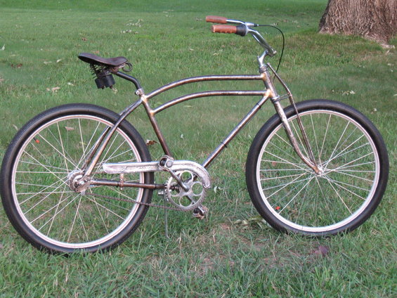 Rusty metal bicycle with brown handlebars and seat, parked on grass