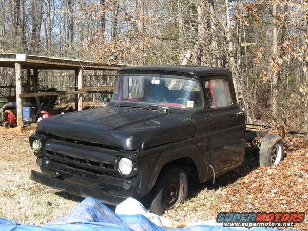 Black pickup truck with missing rear end, parked outdoors near a shed