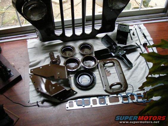 Jeep grille and various engine parts laid out on a cloth
