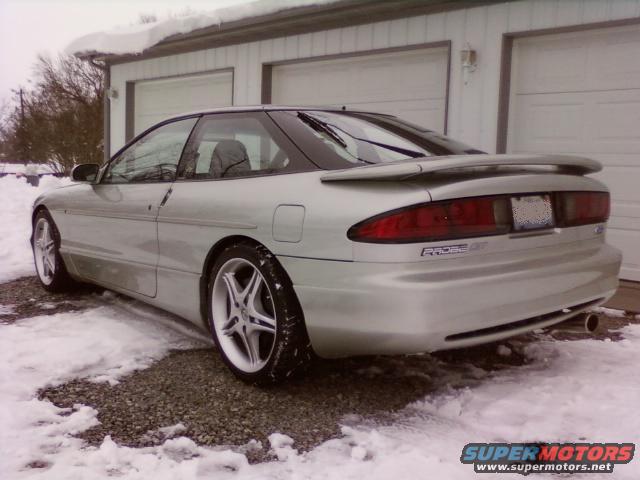 Silver 1994 Ford Probe GT parked in snow, rear 3/4 view. Supermotors.net watermark visible