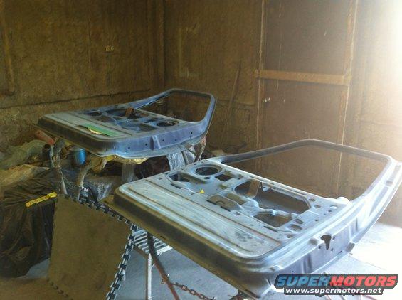 Two disassembled car doors on stands in a workshop