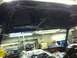 1982 Ford Bronco - Two people are working on a car interior, with another vehicle visible in the background of the shop.