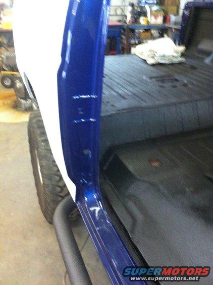 Interior view of a vehicle showing blue and white painted door frame and black floor matting