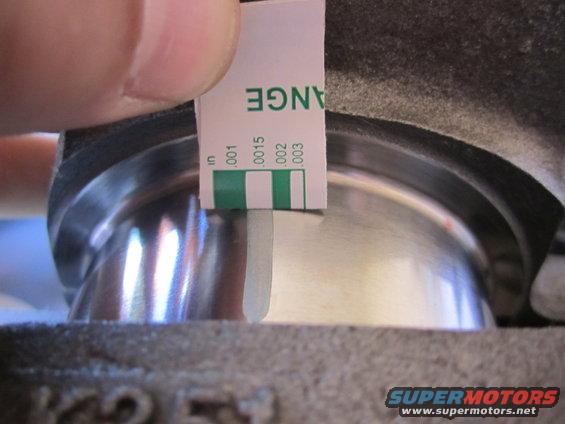 Feeler gauge measuring clearance on engine component. Text on gauge reads 'CHANGE' and measurements in inches