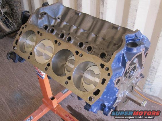 Blue engine block with pistons on an orange stand