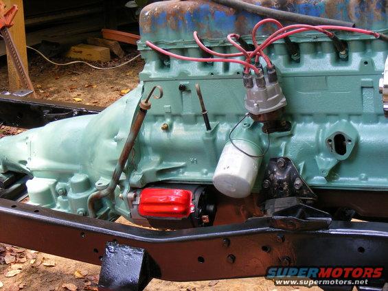 engine and transmission assembly, painted green, with red starter motor and oil filter