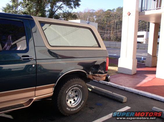 Dark green SUV with tan top, rear damage. 1995 Ford Bronco