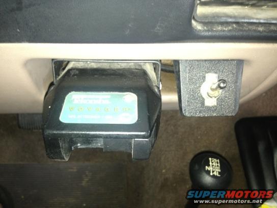 Trailer brake controller with green lights and a toggle switch next to a 4x4 shifter