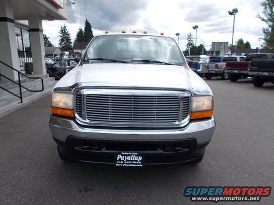Front view of a 2001 Ford F-350 pickup truck with a chrome grille and headlights. Other trucks are parked in the background