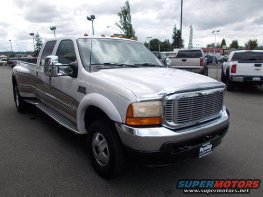 White 2001 Ford F-350 Super Duty dually truck, front 3/4 view, chrome grille, chrome bumper, chrome side steps, brown pinstripes