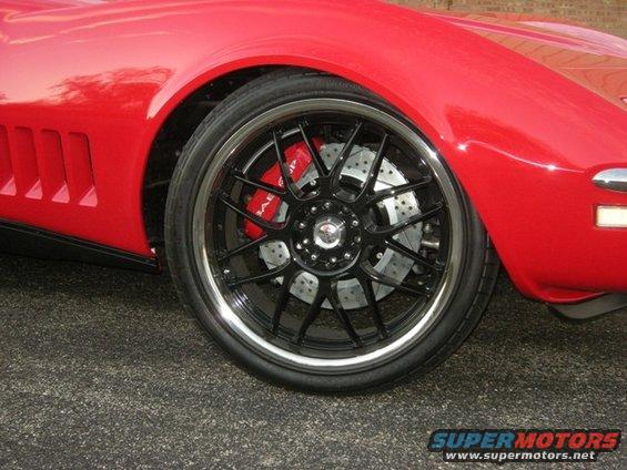 Red sports car wheel with custom black rims and drilled rotors