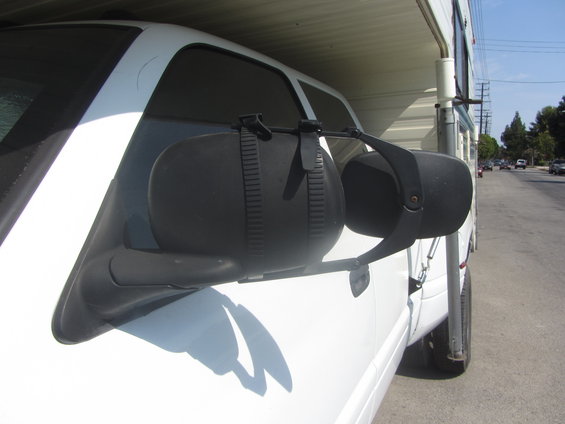 Side view of a white truck with large black towing mirrors attached