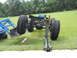 1992 Ford Bronco - A vehicle chassis with oversized tires is being worked on, with a tractor loader and a floor jack assisting.