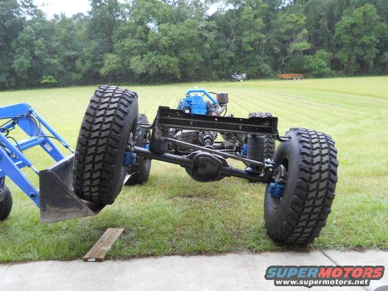 Chassis with large tires and blue engine, front view. Supermotors.net logo visible