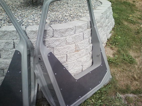 Two car doors with black sound deadening material attached to the inner panels