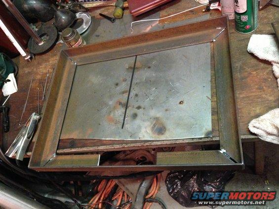 Welded metal frame and sheet metal on a workbench with tools and supplies