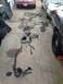 2004 Ford Crown Victoria - Multiple vehicle wiring harnesses are laid out on a concrete driveway, with parts of two cars visible in the background and foreground.