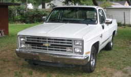White Chevrolet pickup truck parked on grass in front of a house