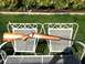 1989 Ford Bronco - A rifle is displayed outdoors on a white metal bench in front of a grassy lawn and bushes.
