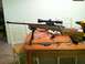 1989 Ford Bronco - A rifle with a scope and bipod rests on a table next to tools and a magazine.