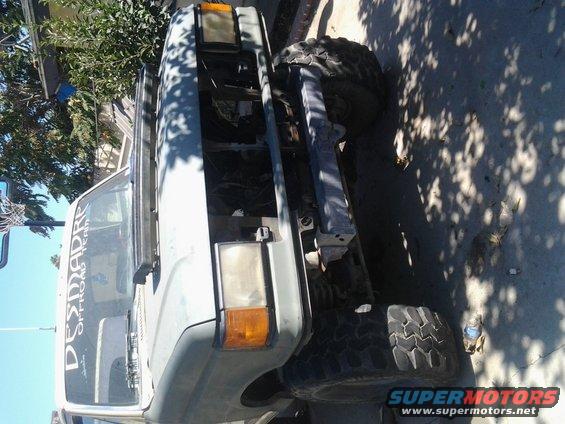 Front end of a lifted truck with large tires, hood open, and 'DESMADRE OFFROAD TEAM' sticker on windshield