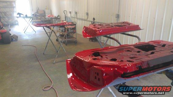 Two red car doors on sawhorses in a workshop