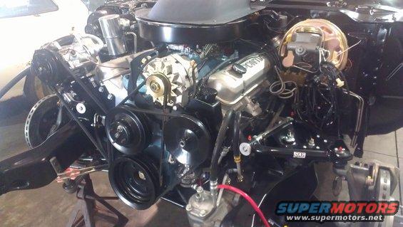 Pontiac V8 engine with alternator, belts, and brake booster visible. Text on valve cover reads 'Pontiac'