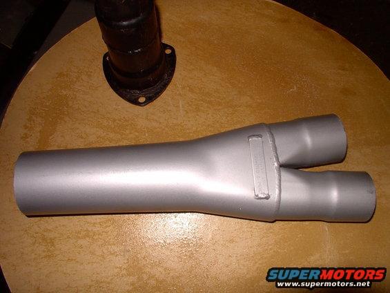 Exhaust Y-pipe with a rectangular stamped section. Part of a black exhaust pipe is visible at the top left