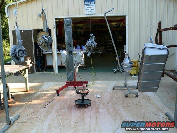 Car parts hanging and on stands in front of a garage