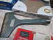 2004 Aston Martin Virage - A collection of tools and tool packaging, including a chisel and a grinding wheel.