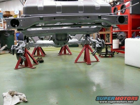 Vehicle frame and suspension on red jack stands in a workshop