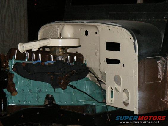 Engine bay with turquoise block, brown intake manifold, and white air cleaner. Body panels are cream and dark green