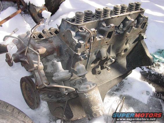 Engine block with spark plugs and distributor sitting in snow