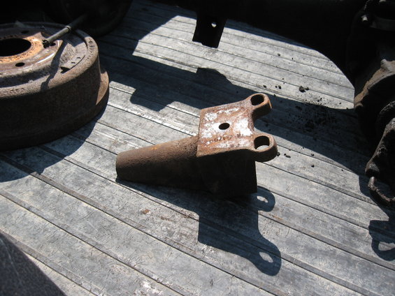 Rusty metal part with two holes on a wooden surface