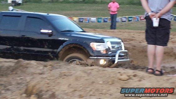 Black Ford F-150 stuck in a mud pit, front end buried
