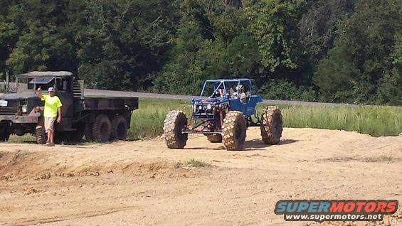 Military truck parked next to a blue off-road buggy with large tires