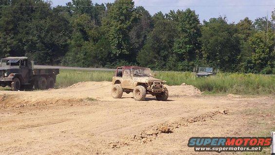 Muddy off-road vehicle being towed by a military truck