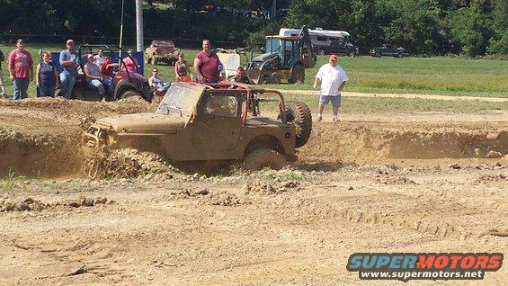 Jeep Wrangler stuck in a mud pit with people watching