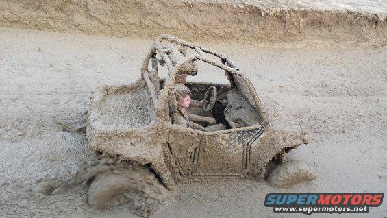 Mud-covered off-road vehicle with a person inside, stuck in thick mud