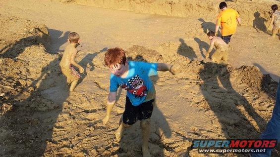 Children covered in mud playing in a muddy pit