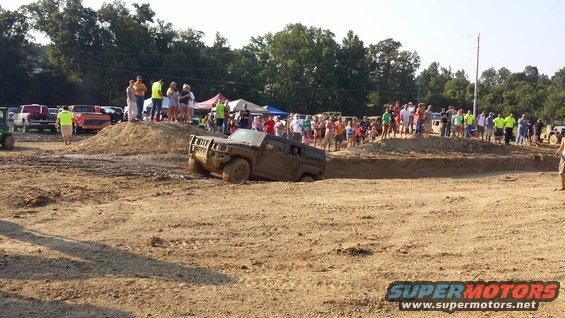 Muddy SUV stuck in a ditch with people watching