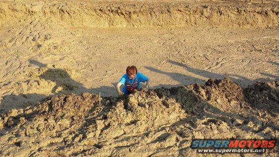 Child in a dirt ditch, Supermotors logo visible